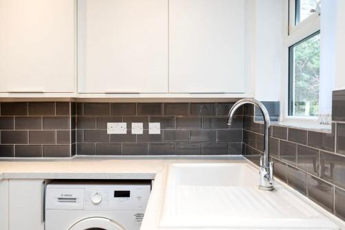 een witte keuken met een wastafel en een vaatwasser bij Lovely 2BR house in Norwood Junction London in Londen