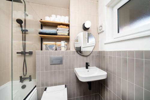 a bathroom with a sink and a shower and a mirror at Cozy 1 bedroom flat at Earlsferry Way in London