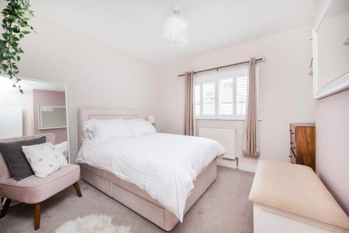Lovely 2BR house in Norwood Junction London في لندن: غرفة نوم بيضاء بسرير وكرسي
