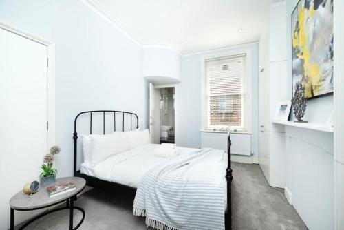 a white bedroom with a bed and a table at Cozy 1 bedroom flat in Greater London in London