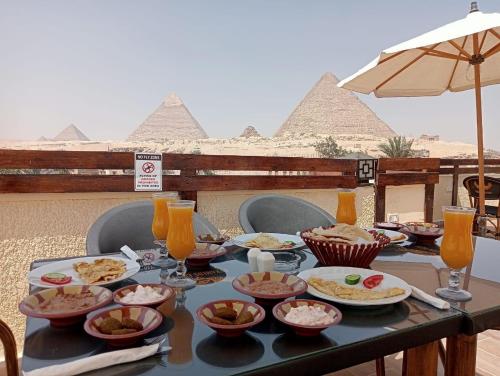a table with plates of food on top of the pyramids at Pyramids Era View in Cairo