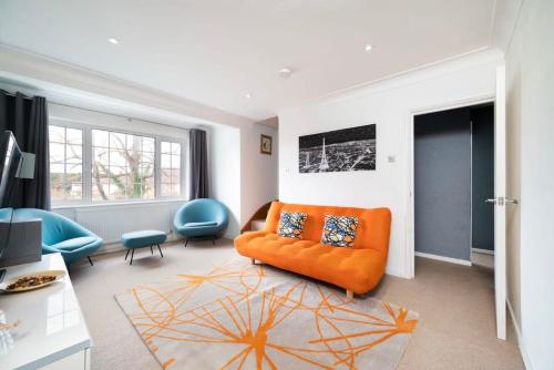 a living room with an orange couch and blue chairs at Delightful 3BR family house in Thames Ditton