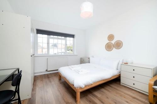 a white bedroom with a bed and a window at Stylish 2BR Oasis Steps from Wembley Stadium in London