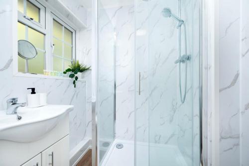 a white bathroom with a shower and a sink at Stylish 2BR Oasis Steps from Wembley Stadium in London