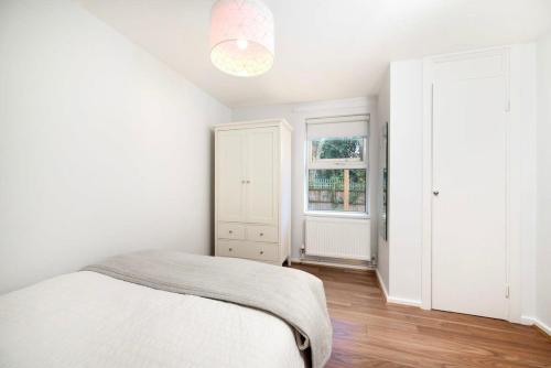 a white bedroom with a bed and a window at Charming 1BR flat with patio perfect for couples in London