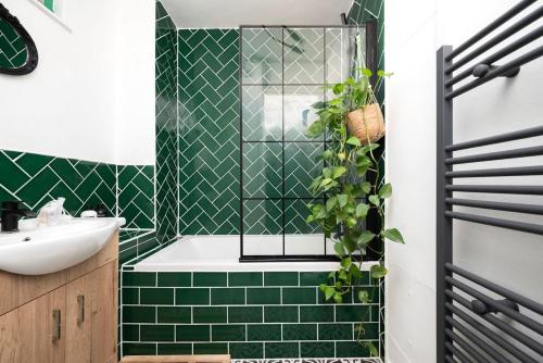 een groene betegelde badkamer met een bad en een wastafel bij Cozy 1-Bedroom Oasis with Balcony in London's Heart in Londen