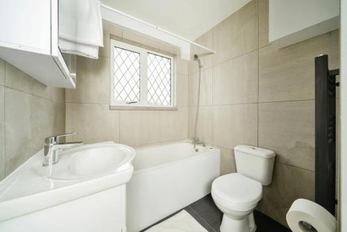 a white bathroom with a sink and a toilet at Charming 3BR House With Free Parking and Garden in Hounslow