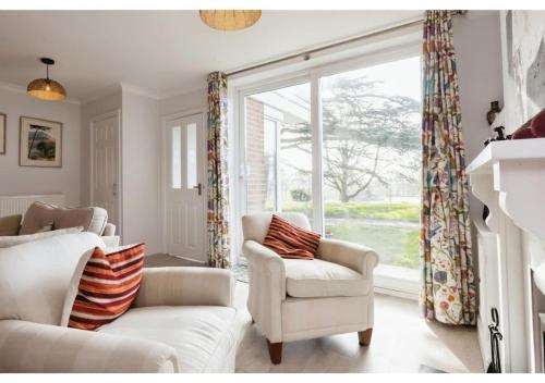 a living room with two white chairs and a large window at 3BR Cheltenham Home - Elegance and Comfort in Cheltenham