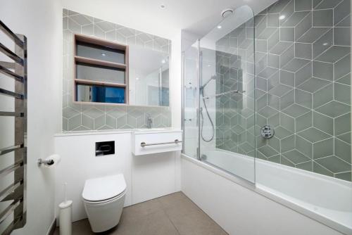 a white bathroom with a shower and a toilet at Chic 2BR Flat in Greater London in London