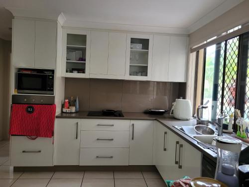 a kitchen with white cabinets and a red towel at Holiday Style A downstairs room in Springwood Qld in Springwood