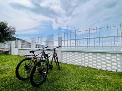 two bikes parked in the grass next to a fence at Seaview Mini Chalet by StayCo - DIRECT BEACH ACCESS in Tanjung Bungah