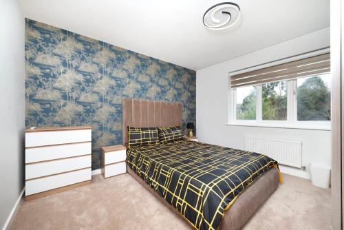 a bedroom with a bed and a blue and white wall at Chic and Spacious 3BR Family Home with Garden in Northolt