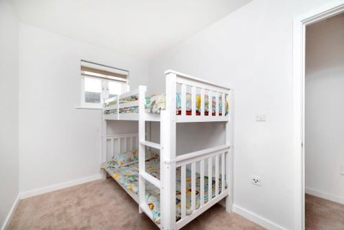 a white bunk bed in a white room at Chic and Spacious 3BR Family Home with Garden in Northolt