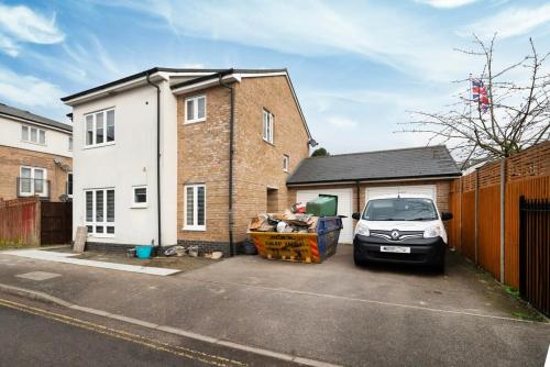a car parked in a parking lot next to a house at Chic and Spacious 3BR Family Home with Garden in Northolt