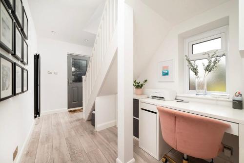a white kitchen with a desk and a pink chair at Charming 2BR House with Garden in Shepperton
