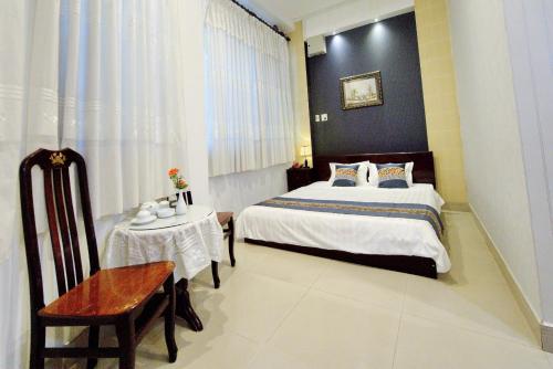 a bedroom with a bed and a chair and a table at Hotel Hải Châu in Chau Doc