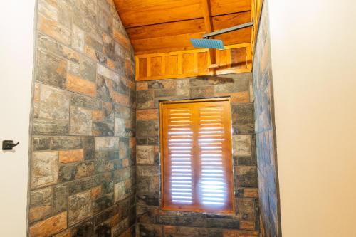 a bathroom with a stone wall and a window at La Fortuna Natural Green in Fortuna