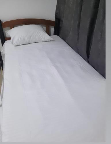 ein weißes Bett mit einem Kopfteil aus Holz und einem weißen Kissen in der Unterkunft Casa Rosimar in Cartagena de Indias