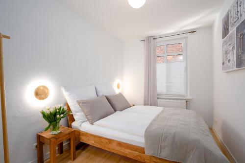 een witte slaapkamer met een bed en een raam bij AMW18 Ferienwohnung Alte Liebe in Häven