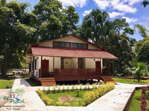 una pequeña casa con porche en un parque en Hostería Finca El Pigual, en Puyo