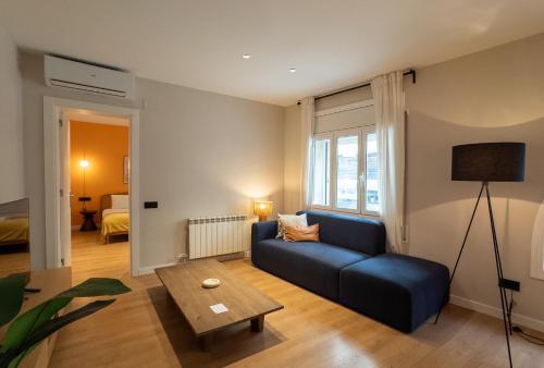un soggiorno con divano blu e tavolo di Stay U-nique Apartments Balmes II a Barcellona
