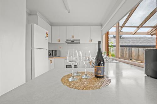 a bottle of wine and two wine glasses on a counter at StayAU 3BRM Family Home Netflix Pet-Friendly in Narre Warren South