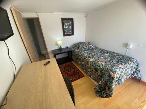 a small bedroom with a bed and a table at NEW HOTEL CRUZ DEL SUR in Concepción