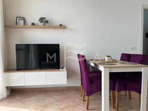 comedor con TV y mesa con sillas moradas en Oceanfront Oasis 770, en Durrës