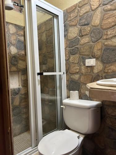 a bathroom with a toilet and a glass shower at AIDA HOSTAL in Flores