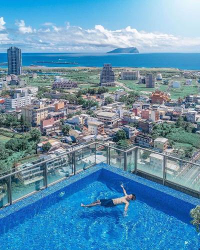 a man laying in a swimming pool on top of a building at 光嶼海溫泉海景無邊際泳池豪華套房 in Hsin-hsing