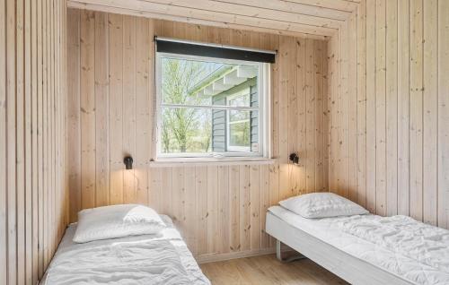 two beds in a wooden room with a window at Beautiful Home In Idestrup With Kitchen in Marielyst