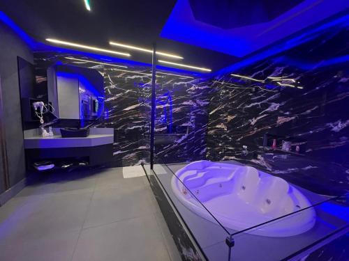 uma casa de banho com banheira num quarto com luzes azuis em Prestige Motel 4 em Sorocaba