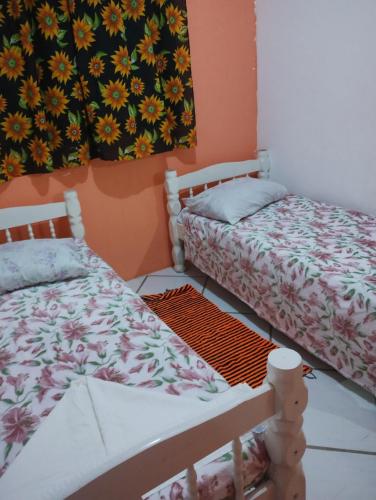 a bedroom with two beds and a painting on the wall at Hostel Raio de Fogo in Paraty