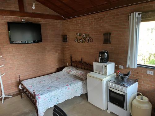 a small room with a small bed and a microwave at Chalé Póca in Conceição da Ibitipoca