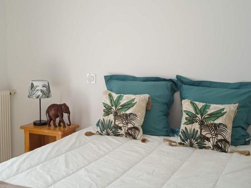 un lit avec des oreillers bleus et un cheval sur une table dans l'établissement Maison Cosy, Rénovée, Proche Plage et Centre, Jardin, Animaux Bienvenus - FR-1-652-19, à Saint-Jean-de-Monts