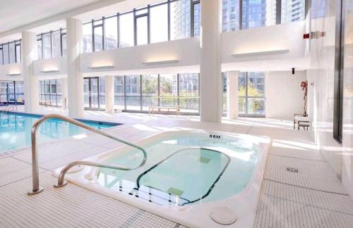 a large pool with a hot tub in a building at CN Tower View w/ Free Parking, Pool & Gym and More in Toronto