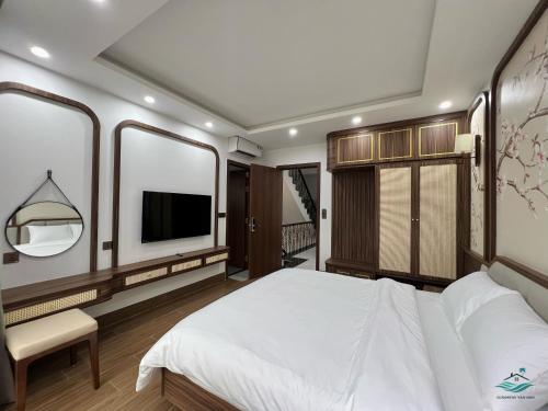 a bedroom with a white bed and a tv at Rosa Villa - Sonasea - Vân Đồn in Thâm Câu