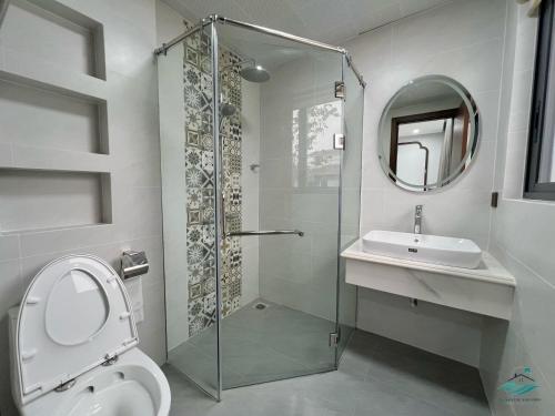 een badkamer met een douche, een toilet en een wastafel bij Rosa Villa - Sonasea - Vân Đồn 