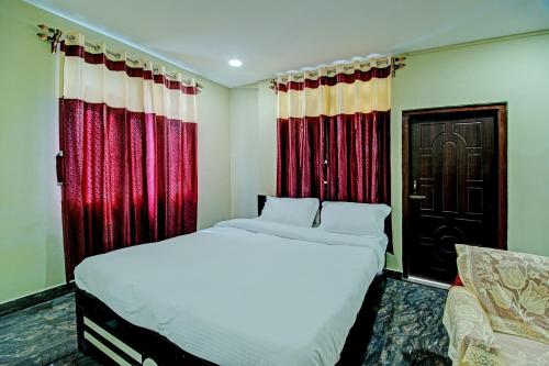 um quarto com uma cama branca e cortinas vermelhas em OYO Vati Guesthouse em Borpāni