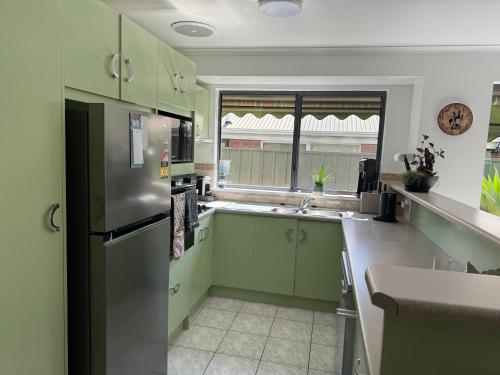 a kitchen with green cabinets and a stainless steel refrigerator at Cin Cin at Mclaren in McLaren Vale