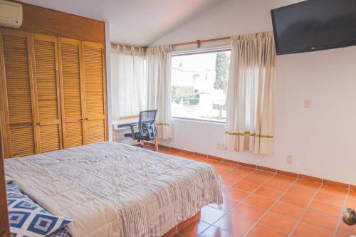 a bedroom with a bed and a large window at Casa Vacacional, Lomas Cocoyoc in Texcalpan