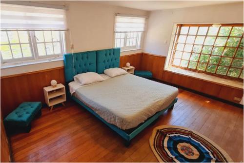 a bedroom with a bed with a blue headboard and windows at Hostal Casona del Mar Parking free in Viña del Mar