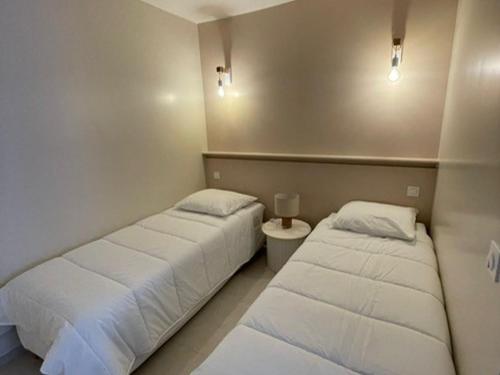 deux lits dans une chambre avec des draps blancs dans l'établissement Appartement Charmant Proche Étang et Thermes avec Jardin Privatif - FR-1-503-177, à Balaruc-les-Bains