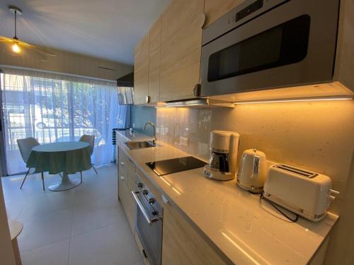 une cuisine avec un comptoir avec un micro-ondes dans l'établissement Appartement Charmant Proche Étang et Thermes avec Jardin Privatif - FR-1-503-177, à Balaruc-les-Bains