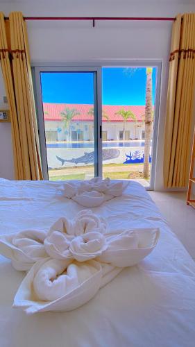 a bed with white sheets and a window with a view at Green Mango Resort in Danao