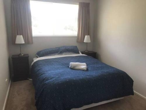 1 dormitorio con 1 cama con manta azul y ventana en Forests Edge en Katoomba
