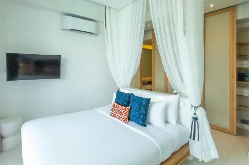 a bedroom with a white bed with blue pillows at Bandara Pool Villas, Phuket in Panwa Beach