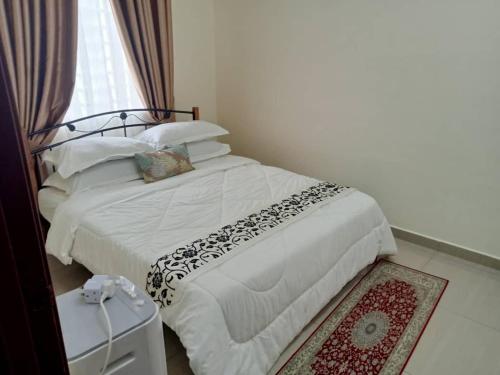 Schlafzimmer mit einem Bett, einem Fenster und einem Teppich in der Unterkunft Homestay Astana Bonda Ibu in Merlimau