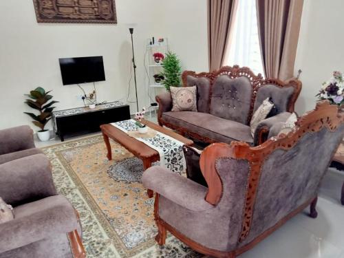ein Wohnzimmer mit 2 Stühlen und einem Tisch in der Unterkunft Homestay Astana Bonda Ibu in Merlimau