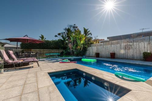 a swimming pool in a backyard with a table and chairs at Oakdean Resort- Pool, Spa, Beach, Sleep 9 in Ocean Grove